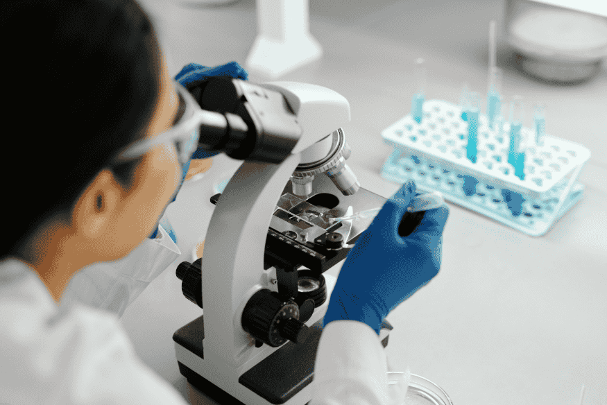 Cientista analisando amostras em microscópio para pesquisa em biotecnologia moderna