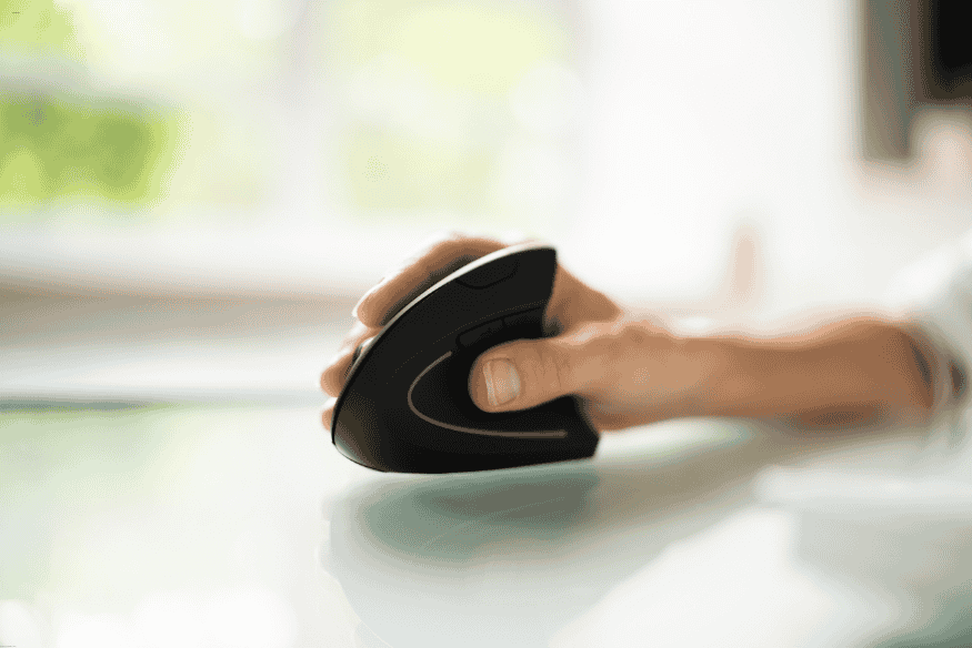 Mão utilizando mouse ergonômico vertical sobre mesa clara