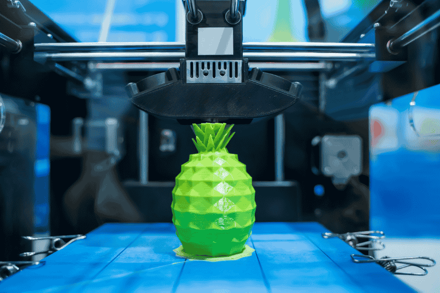 Impressora 3D fabricando modelo de abacaxi, representando inovações na gastronomia digital.