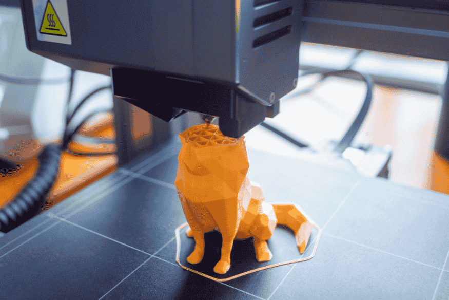 Impressora 3D produzindo figura de cachorro, simbolizando aplicação na medicina veterinária.