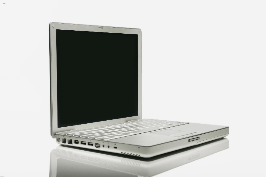 Notebook prata com tela desligada, visto em ângulo lateral sobre fundo branco