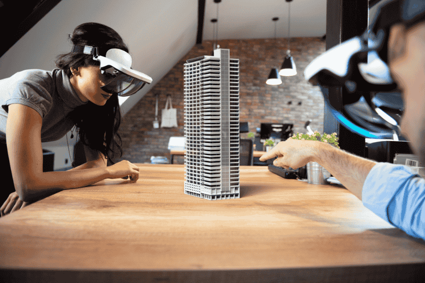 Duas pessoas usando óculos de realidade mista para visualizar maquete virtual de edifício