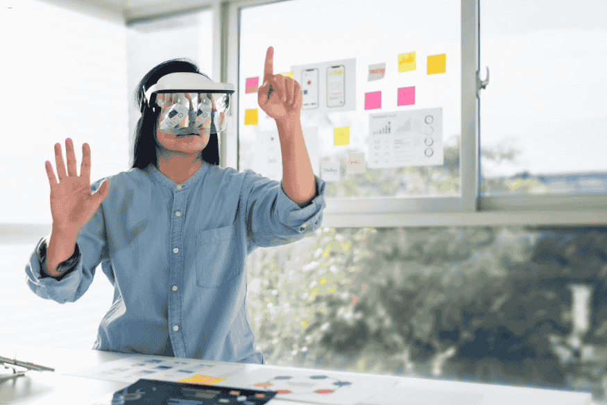 Mulher com óculos de realidade mista interagindo com interface virtual no ambiente de trabalho