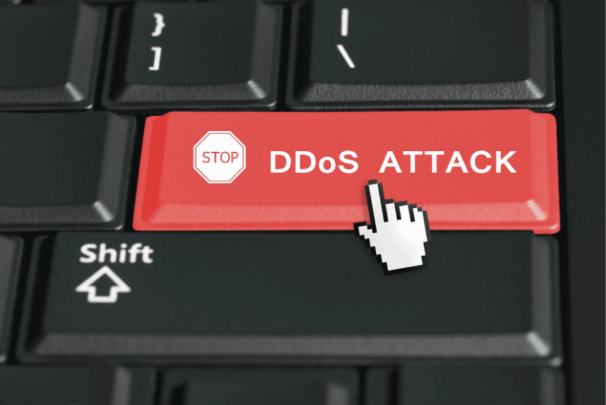 Tecla vermelha com mensagem “Stop DDoS Attack” em teclado de computador.