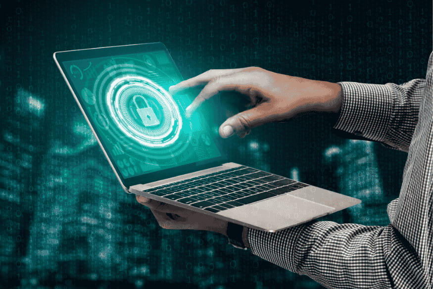 Mão tocando tela de laptop com holograma de segurança, ilustrando gestão de privacidade digital.
