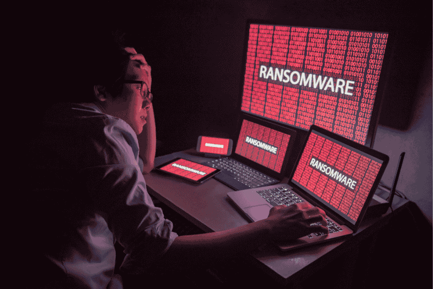 Homem preocupado diante de vários dispositivos infectados por ransomware