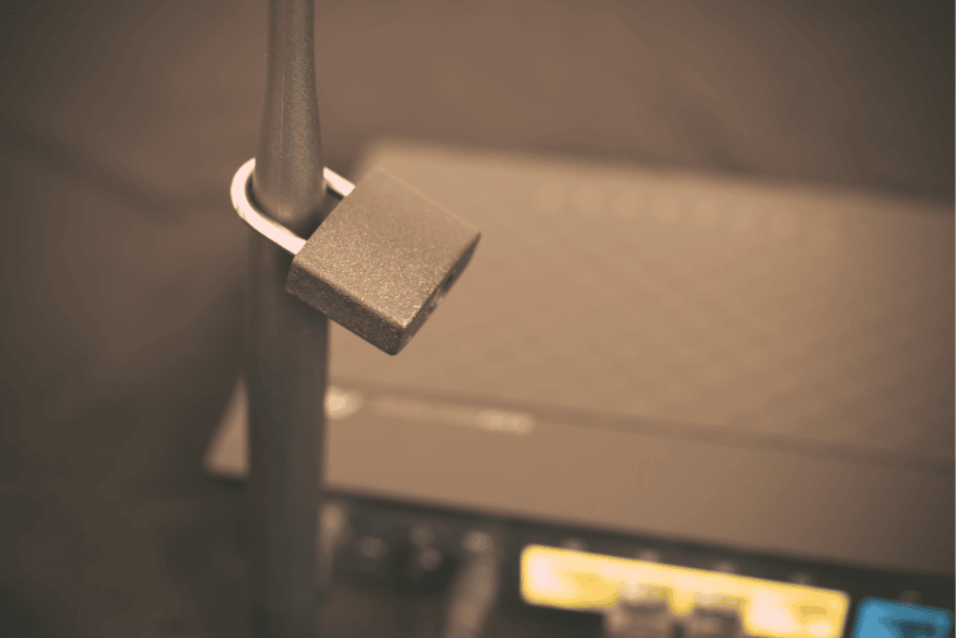 Antena de roteador com cadeado preso, simbolizando a proteção física e digital da rede Wi-Fi.