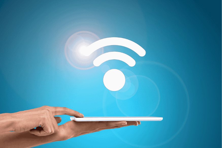 Mão segurando tablet com ícone de sinal Wi-Fi, indicando acesso seguro à internet doméstica.