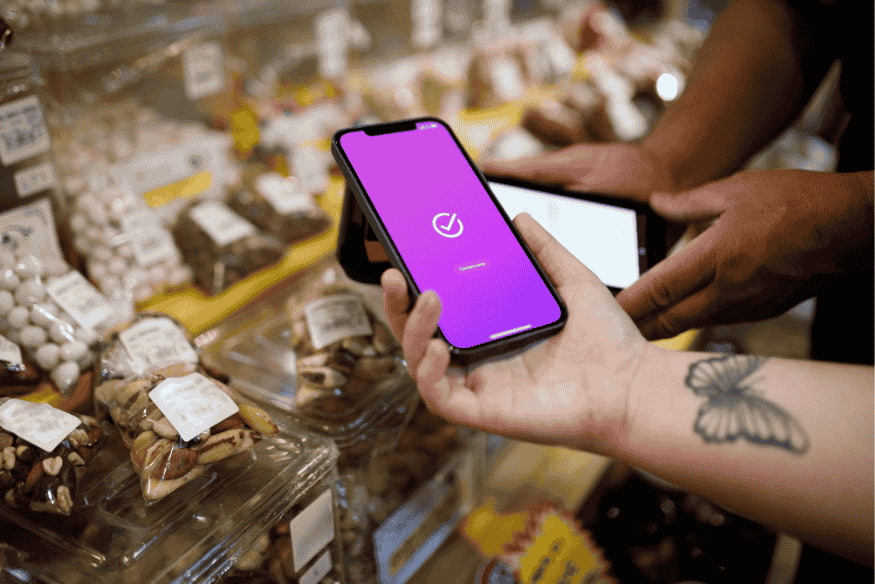 Pessoa usando celular com pagamento por aproximação em loja de varejo.