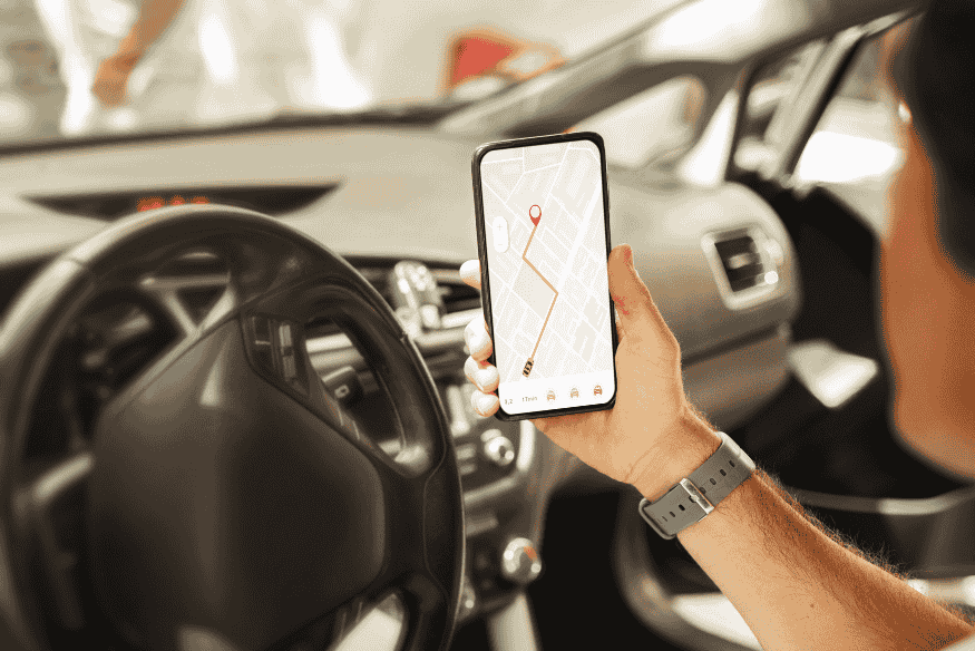 Motorista segurando smartphone com mapa e rota traçada, simbolizando busca por voz local no celular.